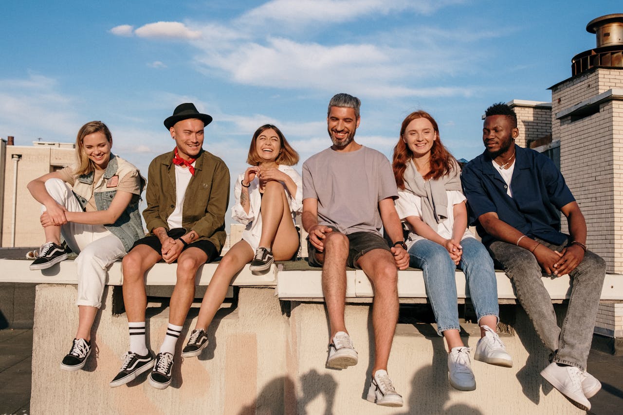Diverse group of friends laughing and relaxing on a sunny rooftop.
