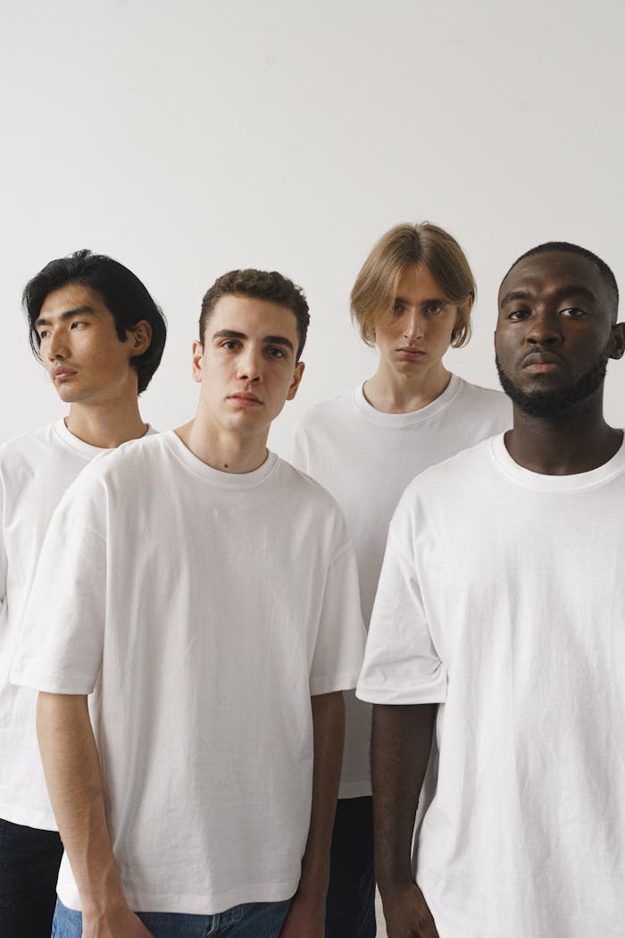 Portrait of a diverse group of young men in white shirts against a white background.